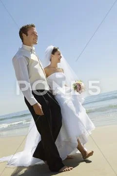 Bride and Groom walking on beach Stock Photos