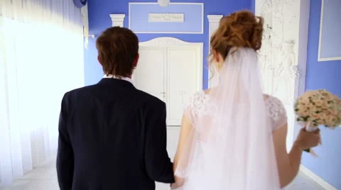 Bride and groom walking down the hall holding hand Stock Footage 66776384