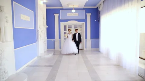 Bride and groom walking down the hall holding hands Stock Footage 66776390