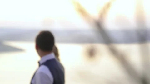 Bride and groom walking down the beach at sunset, refocusing on wedding rings. Stock Footage 221017370