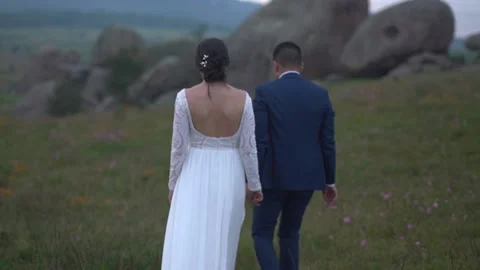 Bride and groom walking in front of big rocks Stock Footage 157499061