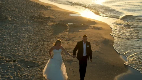 Bride and groom walking next to the sea aerial shot Stock Footage 99493863