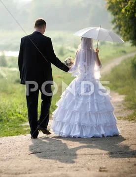 Bride and groom walking in sunlight Stock Photos