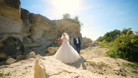 Bride and handsome groom walking near sandy rocks Stock Footage 96000268