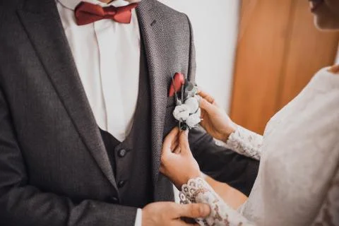 The bride attaches a buttonhole to suit Stock Photos