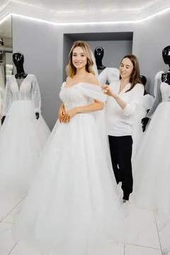 The bride-to-be chooses a dress for the wedding. A dressmaker's assistant i.. Foto stock