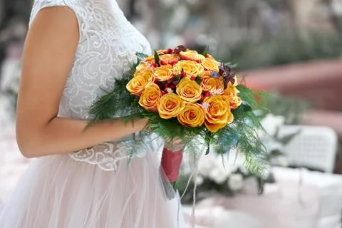 Bride in a beautiful white dress goes holding a wedding bouquet of orange roses Stock Photos