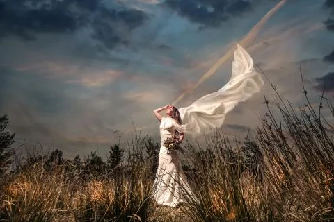 Bride with a bouquest in windy garden Stock Photos