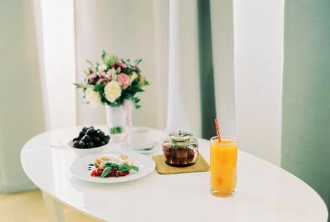Bride breakfast on a white table next to a bouquet of flowers Stock Photos