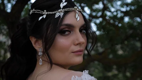 Bride with decoration on head poses against green plants Stock Footage 122000538