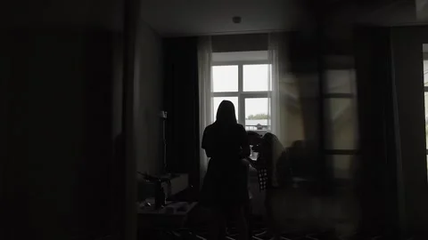 The bride is doing makeup at the big window. Silhouettes by the window. wedding Video stock 306145132