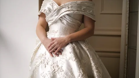 Bride in dress with patterns poses standing near window sill Stock Footage 121810369