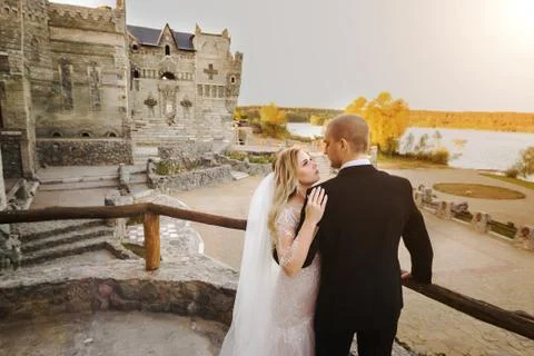 Bride embracing groom while standing near handrails Stock Photos
