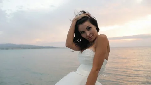 The Bride Enjoys A Beautiful Sunset Standing On The Rocks Near The Sea Video stock 141721901
