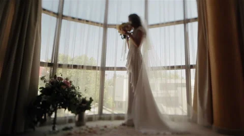 Bride face blurred standing near window smelling wedding bouguet. Tilt shift Stock Footage 62496119