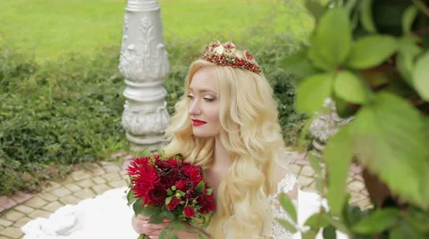 Bride with flowers in hand looking up sitting on the ground. Stock Footage 68446793