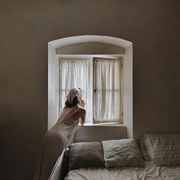 Bride Gazing Out of Window in Soft Light Stock Photos