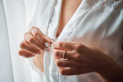 The bride gently holds the wedding ring with beautifully manicured fingers... Stock Photos