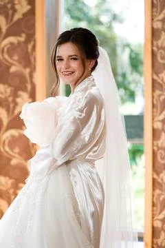 Bride getting ready in a silk robe, holding her wedding dress. A beautiful and Stock-Fotos