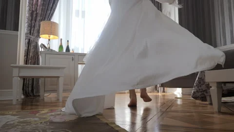 The bride goes to the window in a white robe. A bride in a flowing white gown Stock Footage 284433887