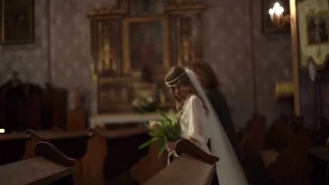 A bride with the groom gracefully walks down the aisle of a historic church Stock Footage 310724490