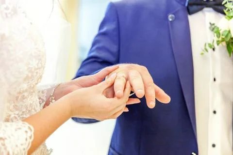 Bride hand putting wedding ring on groom finger Stock Photos