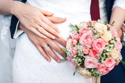 Bride hand with ring and wedding bouquet of flowers Stock Photos