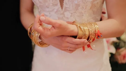 Bride hands and arms with many gold bracelets. Gold gifts from guest presenting Stock Footage 234754516