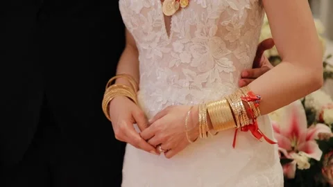 Bride hands and arms with many gold bracelets. Gold gifts from guest presenting Stock Footage 234917637