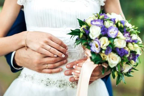 Bride hands with ring and wedding bouquet of flowers Stock Photos