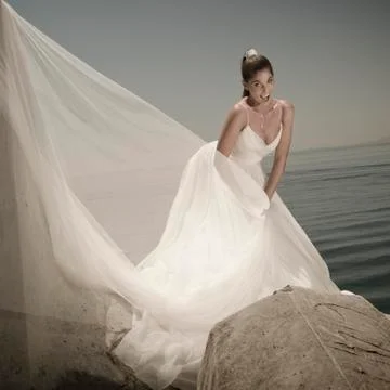 Bride with a happy expression standing on rocks. Stock Photos