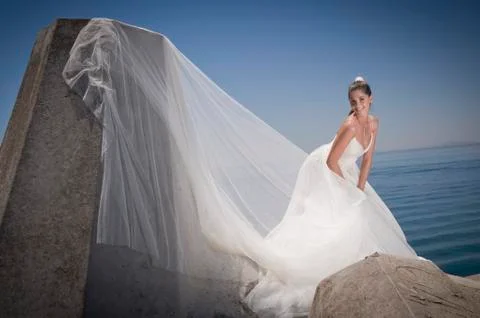 Bride with a happy expression standing on rocks. Stock Photos
