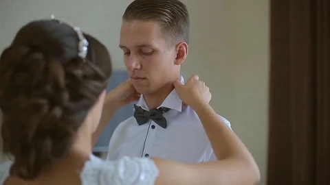 The bride helps the groom to get dressed on the wedding day, the hotel room Stock Footage