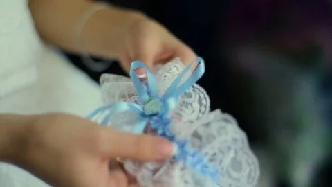 The bride hold in hand a wedding garter and look at window Stock Footage 82977033