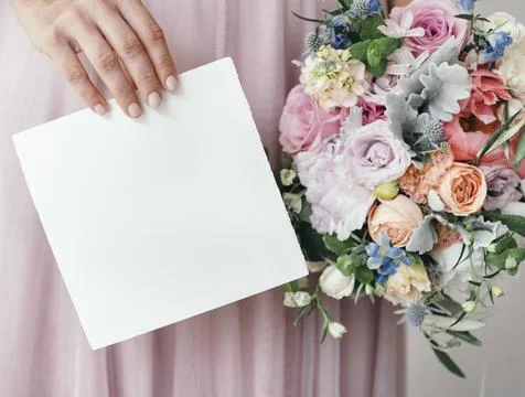 Bride holding a save the date card with a bouquet of flowers Stock Photos