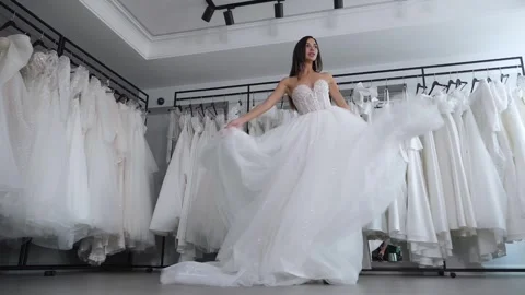 The bride in a long elegant white dress is slowly spinning in the wedding salon. Stock Footage 325180330