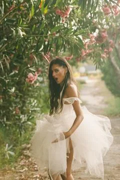 Bride looking back beside pink flowers on a leafy garden path Stock Photos