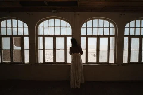 Bride looking outside windows of an old colonial villa Stock Photos
