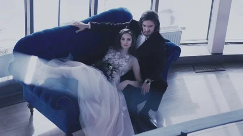 Bride lying on the big blue sofa and caresses her fiance Stock Footage 73377537