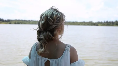 Bride one is standing back to camera looks on at lake Stock Footage 124200154