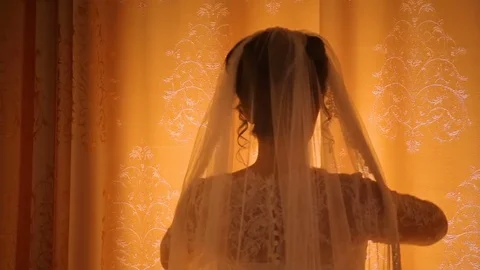 Bride opens beige curtains standing before bright window Stock Footage 75375729