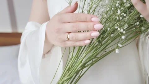 Bride passes hand with wedding ring on bouquet of gypsophila Video stock 189164281
