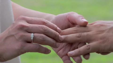 Bride Placing  Wedding Ring on Groom's Finger During Wedding Ceremony Outside Stock Footage 58102942