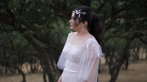 Bride poses looking into distance against green plants Stock Footage 122001273