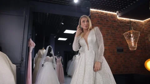 Bride posing gracefully in white wedding gown inside elegant bridal boutique Stock Footage 318270125