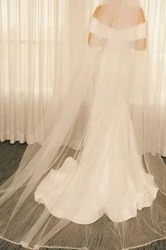 Bride prepares for wedding in long white dress with veil in  bright room with Foto stock