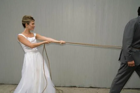 A bride pulling the groom with a rope Stock Photos
