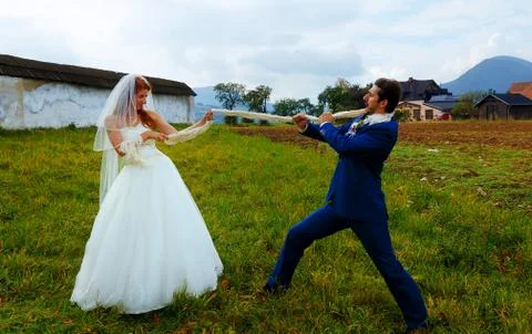 Bride pulling her groom to her with a rope - funny wedding concept Foto stock