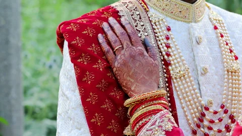 Bride put an arm on the groom , dressed in traditional red and white Indian Stock Footage 310431616