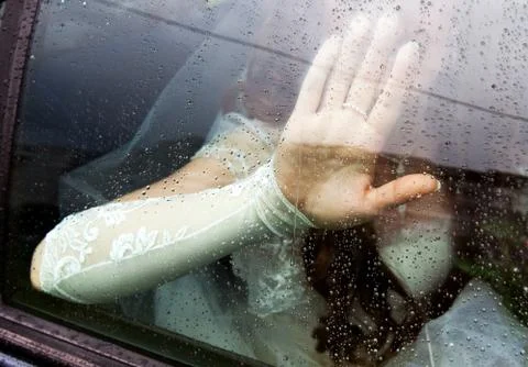 The bride put her hand on the window glass covered with raindrops Foto stock